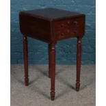 A Victorian mahogany Pembroke table, with dummy drawers to one side, raised on turned legs.