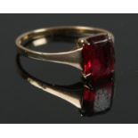 A 9ct gold ring with central red stone. Size M. Total weight: 1.32g.