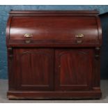 A Victorian mahogany cylinder top desk with lower cupboard, with roll top inclosing fitted