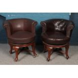 A pair of swivel tub chairs on mahogany supports.