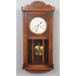 A Edwardian oak cased wall clock. 8 day movement. With pendulum & key (70.5cm height 33.5 cm width)