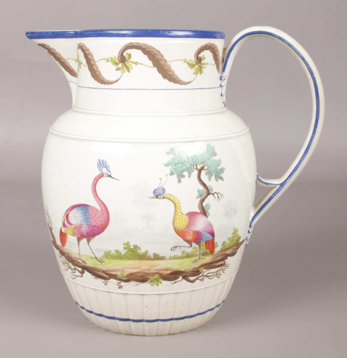 An early 19th century pearlware jug painted in coloured enamels with exotic birds in landscape.
