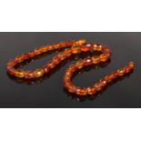 A string of graduated and faceted amber beads. 53cm.