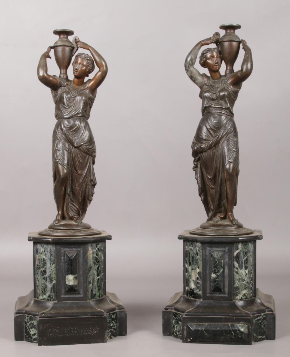 A pair of bronze figures raised on marble plinths modelled as water carriers. 41.5cm.