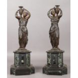 A pair of bronze figures raised on marble plinths modelled as water carriers. 41.5cm.