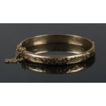 A 9ct gold bangle with engraved decoration. 10.9g.