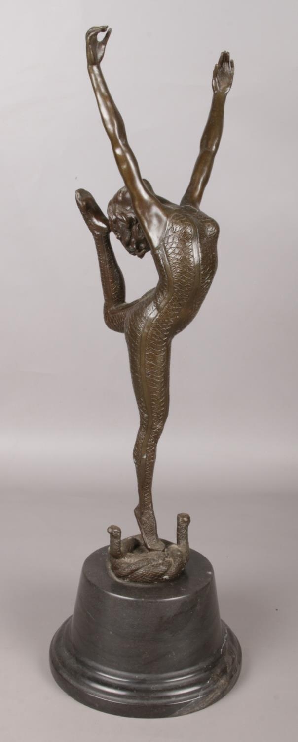 After Otto Poertzel, a bronze sculpture on marble base, modelled as a dancer standing on two snakes.