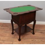 An early 20th century oak games table with fold over top and lined storage compartment.