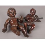 Two carved wooden figures of cherubs in seated positions, the smaller example playing a lute.