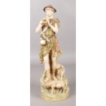 A Royal Dux figure of a shepherd playing pipes with two sheep at his feet. 37cm.
