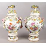 A pair of Dresden porcelain lidded vases on stands. With floral and classical scenes, applied floral