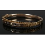 A vintage 9ct gold bangle set with three small diamonds and two sapphires. 9.88g.