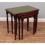 A nest of three mahogany tables with green leather inset tops.