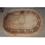 A large oval cream ground rug with floral border and central medallion (290cm x 204cm). Requires a