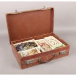 A small leather suitcase containing a large quantity of costume jewellery, including simulated