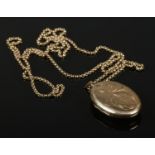 A 9ct gold locket and chain. The locket having engraved scrolling decoration to the front. 18.99g.