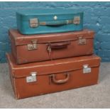 Three vintage suitcases, including blue Revelation example.