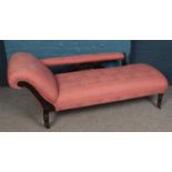 A Victorian carved mahogany chaise long. With red upholstery and turned supports.