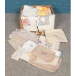 A box containing assorted linens. To include tablecloths, doilies etc.