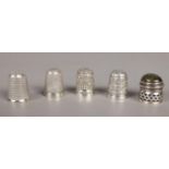 Four silver thimbles along with a small pierced silver pot with hardstone lid.