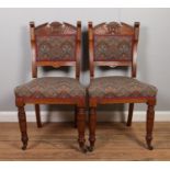 A pair of Edwardian carved mahogany chairs with upholstered seats and backs. Raised on turned