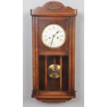An Edwardian oak cased wall clock. 8 day movement. With pendulum & key (70.5cm height 33.5 cm width)