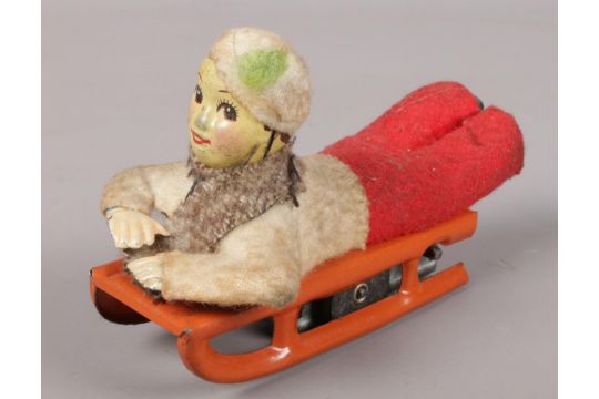 A Fairylite Clockwork figurine of a young boy on sledge. No key.