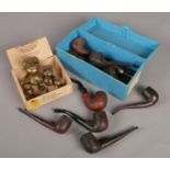 A box of smoking pipes along with a small set of brass weights.