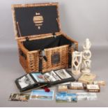 A Harrod's wicker basket with contents. Including album with postcards, two figures, boxed hip