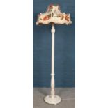 A white painted standard lamp with floral shade.
