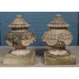A large pair of carved stone lidded garden urns of Neoclassical design, with swag and bow decoration