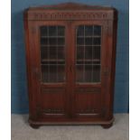 A carved oak bookcase. With lead glazed glass panel doors and linen fold decoration. (130cm x 91cm)