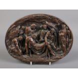 An oval cast metal plaque depicting Jesus descending from the cross. Signed Justin. H:15cm W:20cm.