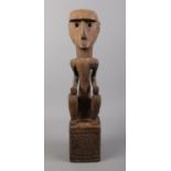 A carved tribal squatting figure. H: 46cm.