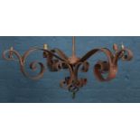 A wrought iron four arm chandelier with scrolling decoration.