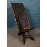 An African hardwood birthing chair. The back is carved with two figures and baby. H: 89cm W: 35cm.