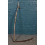 A vintage scythe. H: 155cm. Rusting to the blade and handle.