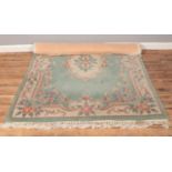 A Chinese floral green wool rug with cream background. (135cm x 200cm)