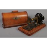 A cased Singer hand crank sewing machine.