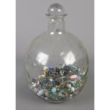 A glass carboy with contents of various marbles.