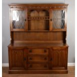 A carved oak dresser with central spindle gallery and lead glazed upper doors. Height: 178cm, Width: