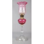 A Victorian cranberry glass oil lamp. (48cm height) Chip to bottom of shade.