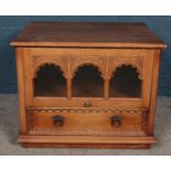 A small oak cabinet with sliding glass panel door.