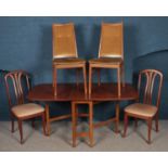 A teak drop leaf kitchen table along with two pairs of chairs.