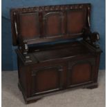 A carved oak monks bench. With fold over back rest and under seat storage.