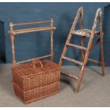 A pine towel rail, together with a large hinged wicker basket and a pair of wooden stepladders.