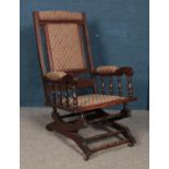 A hardwood American rocking chair, with fabric upholstered seat and backrest, spindle supported arms