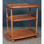 An Ercol three tier serving trolley, in Golden Dawn, with turned tapered pillars, raised on casters.
