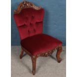 A carved mahogany red upholstered deep buttoned chair.