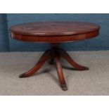A Mahogany circular coffee table resting on four legs with claw feet and concealed draw. H: 53cm